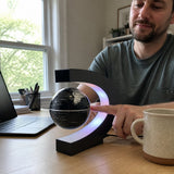 גלובוס מרחף FloatGlobe על שולחן עבודה, אצבע עוברת מתחתיו